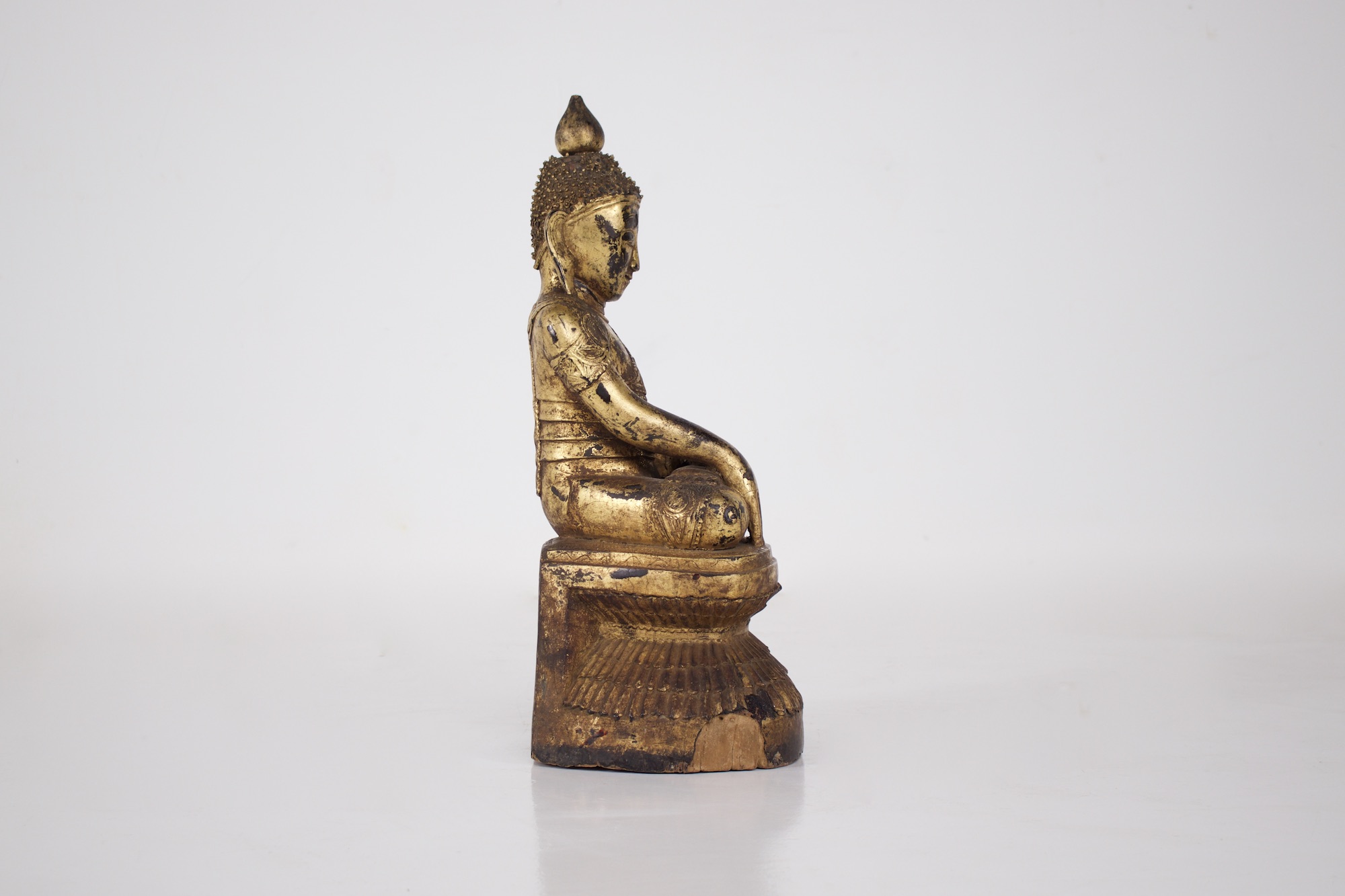 Ancien bouddha en bois sculpté doré du Myanmar vu de profil droit