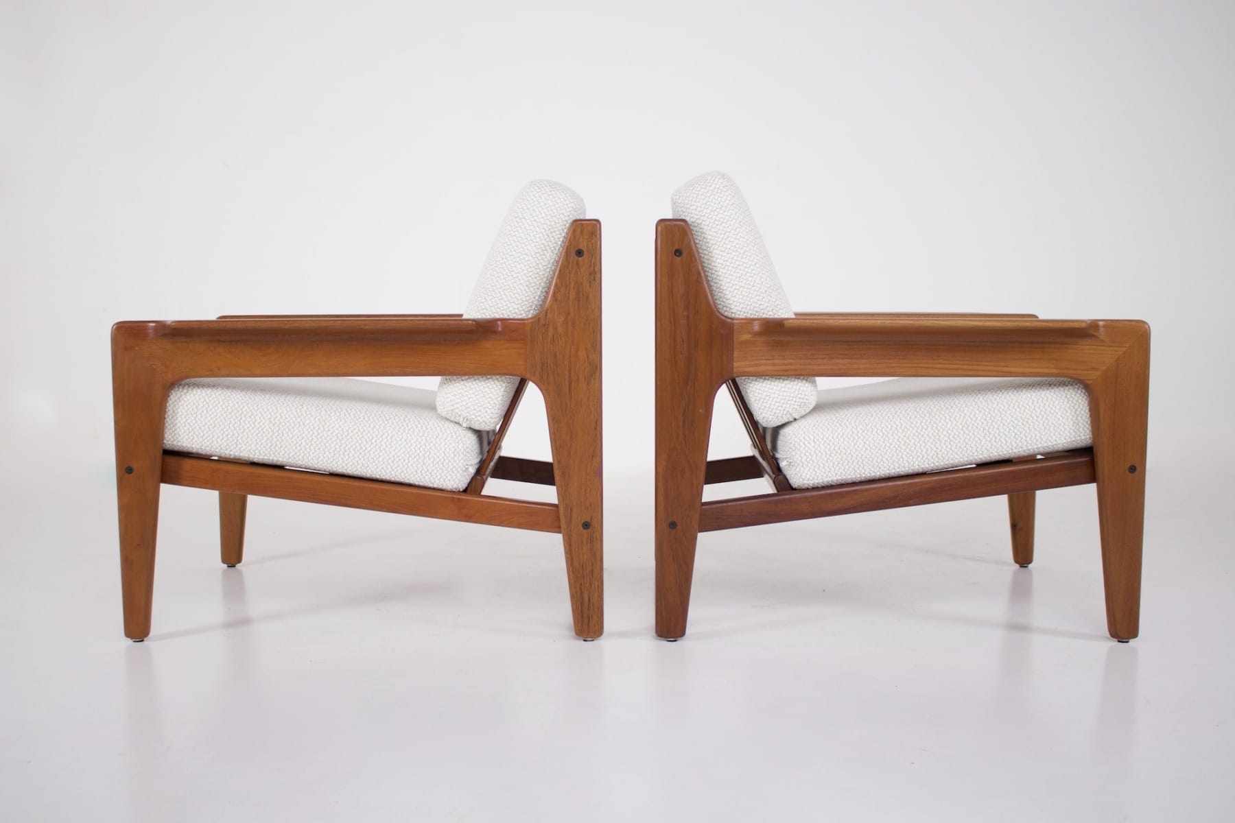 Deux fauteuils scandinaves en teck vus dos à dos.