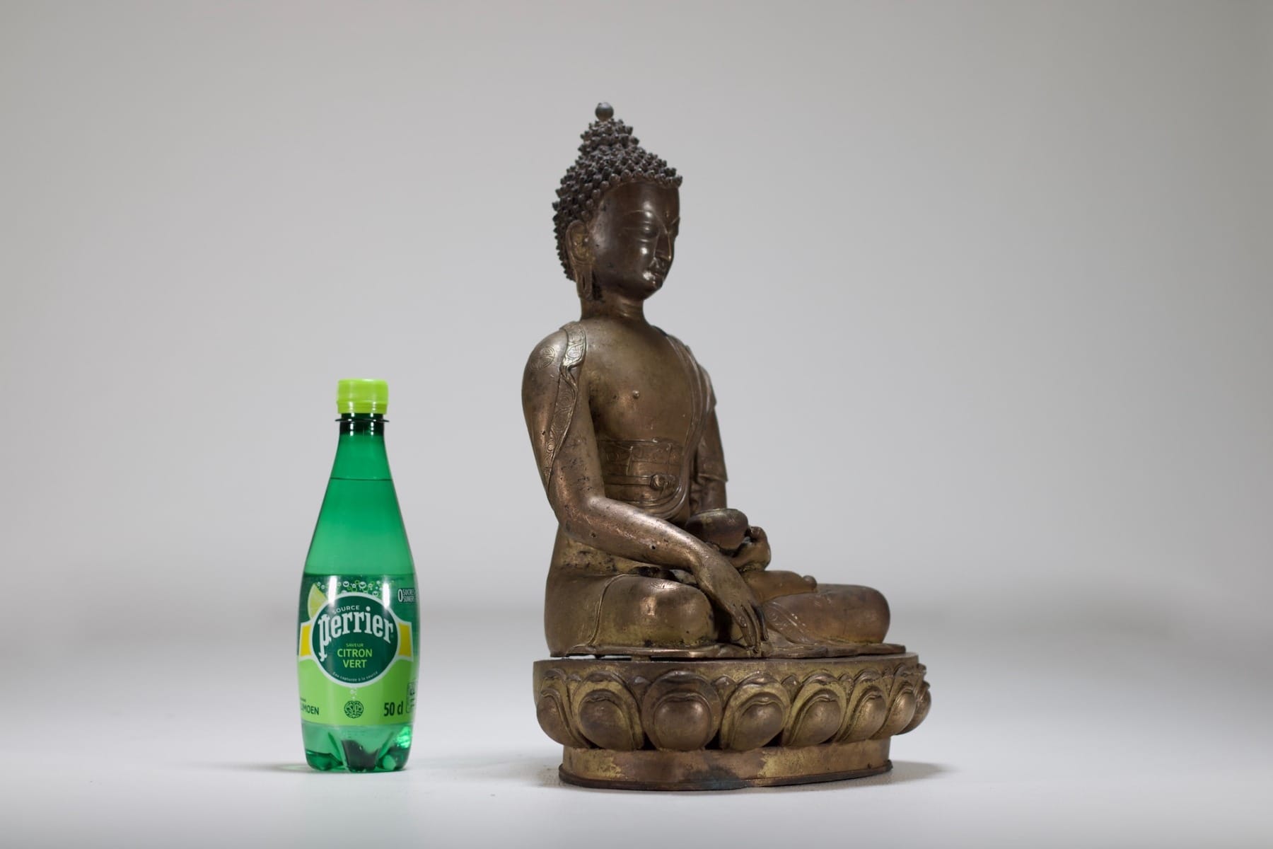 La sculpture anciennede bouddha à côté d'une bouteille d'eau