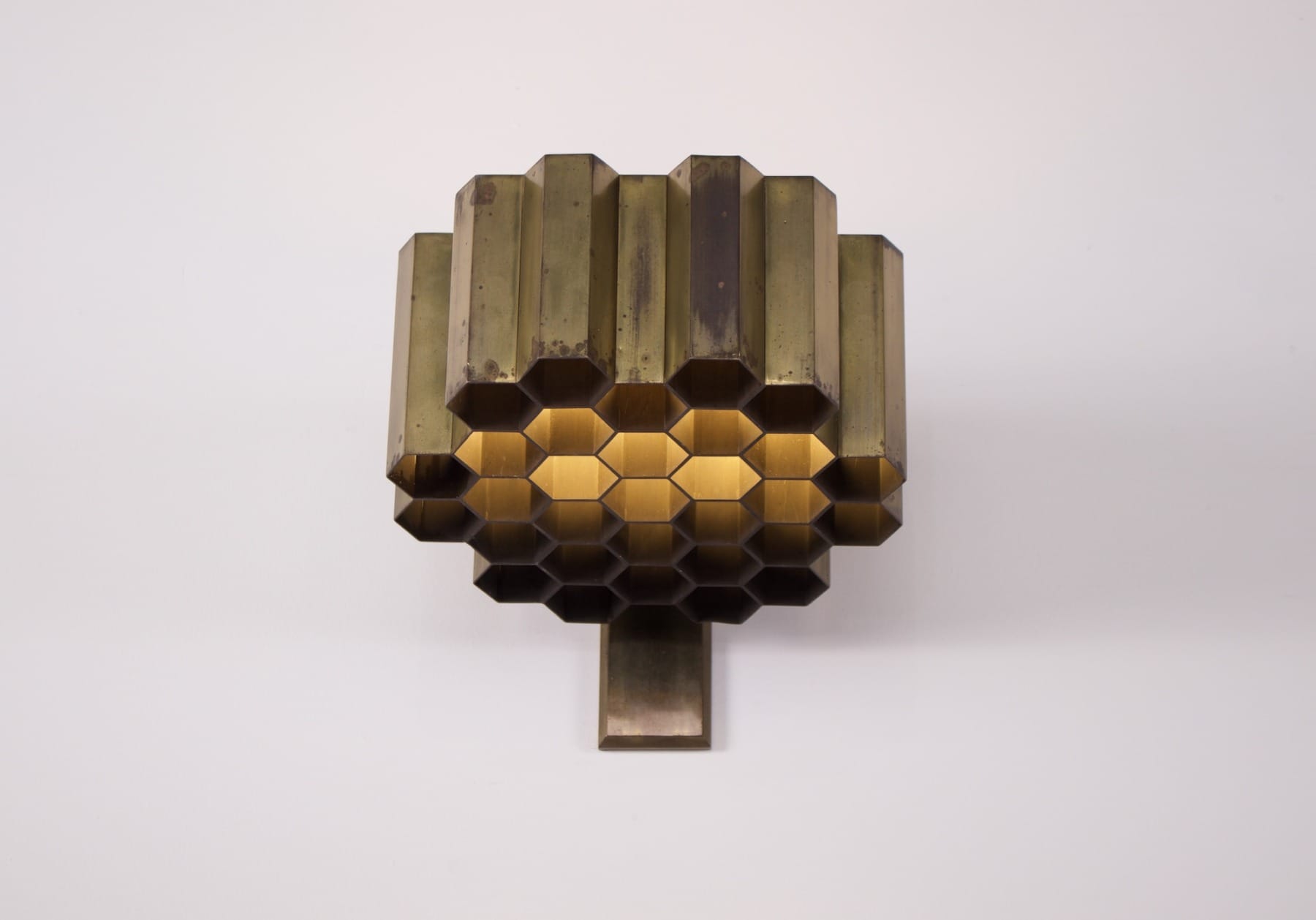 Une applique nid d'abeille en laiton massif de Jules Wabbes allumée vue de dessous