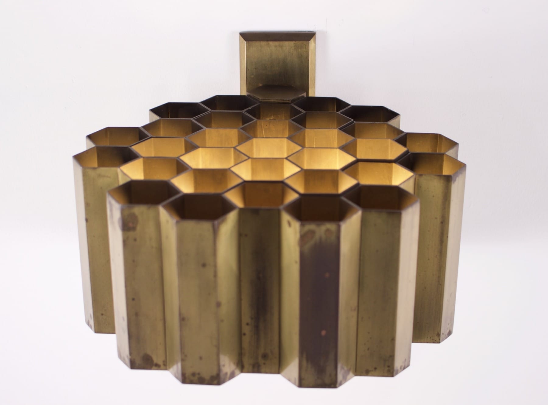 Une applique nid d'abeille en laiton massif de Jules Wabbes allumée de dessus