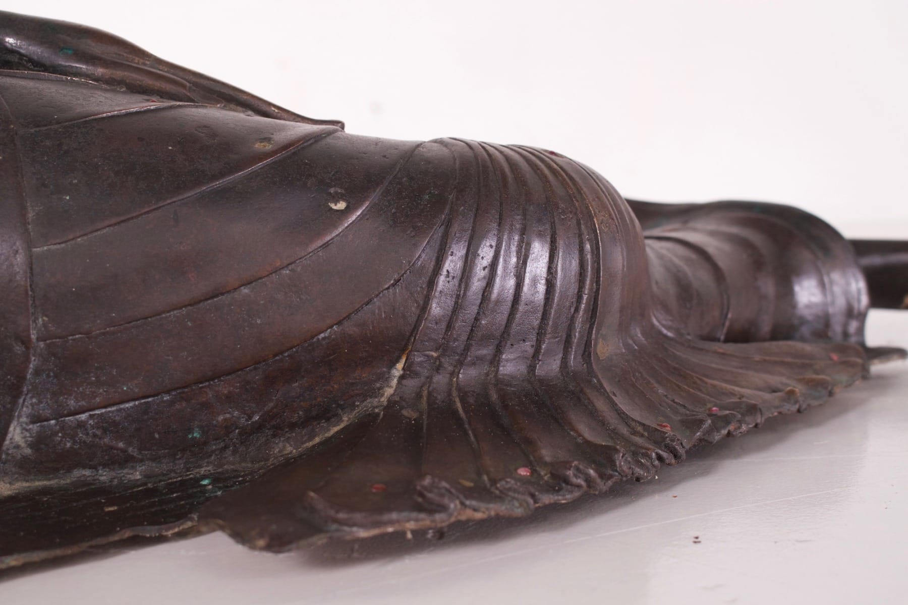 Détail du drapé du Bouddha ancien en bronze couché en paranirvana