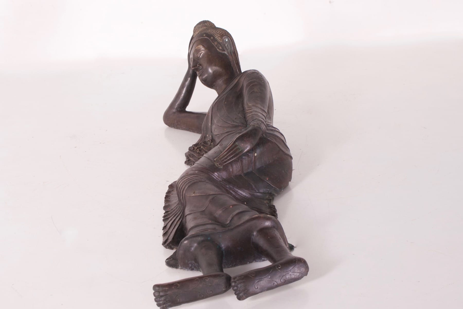 Bouddha ancien en bronze couché en paranirvana vu de profil
