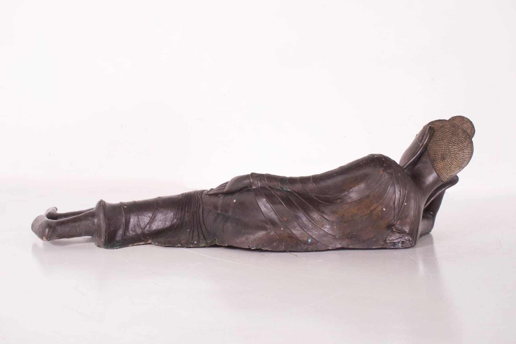 Bouddha ancien en bronze couché en paranirvana vu de dos