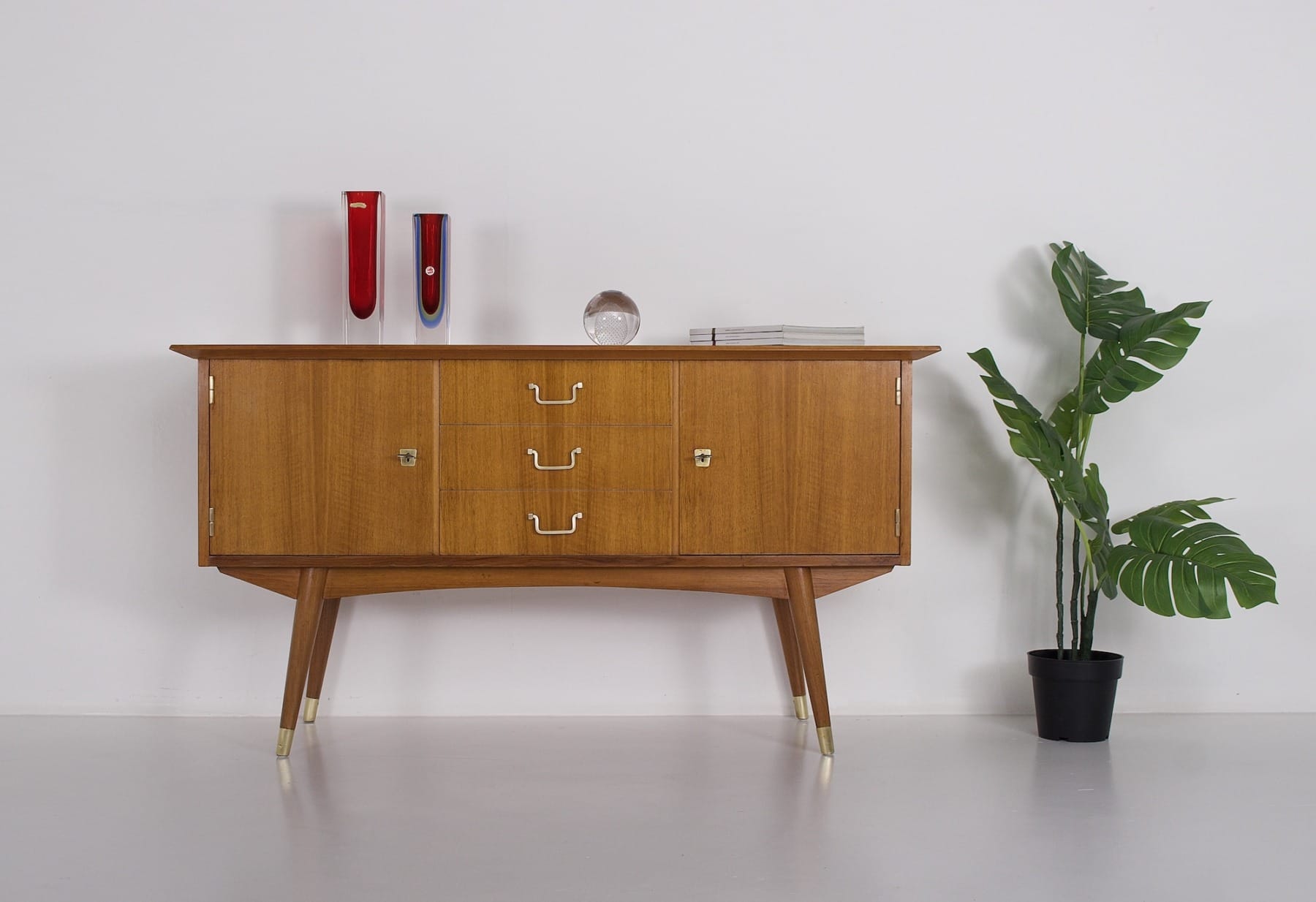Le buffet Moderniste aux côtés d'une plante, des vases val St-Lambert, des magazines et une boule de cristal posés dessus