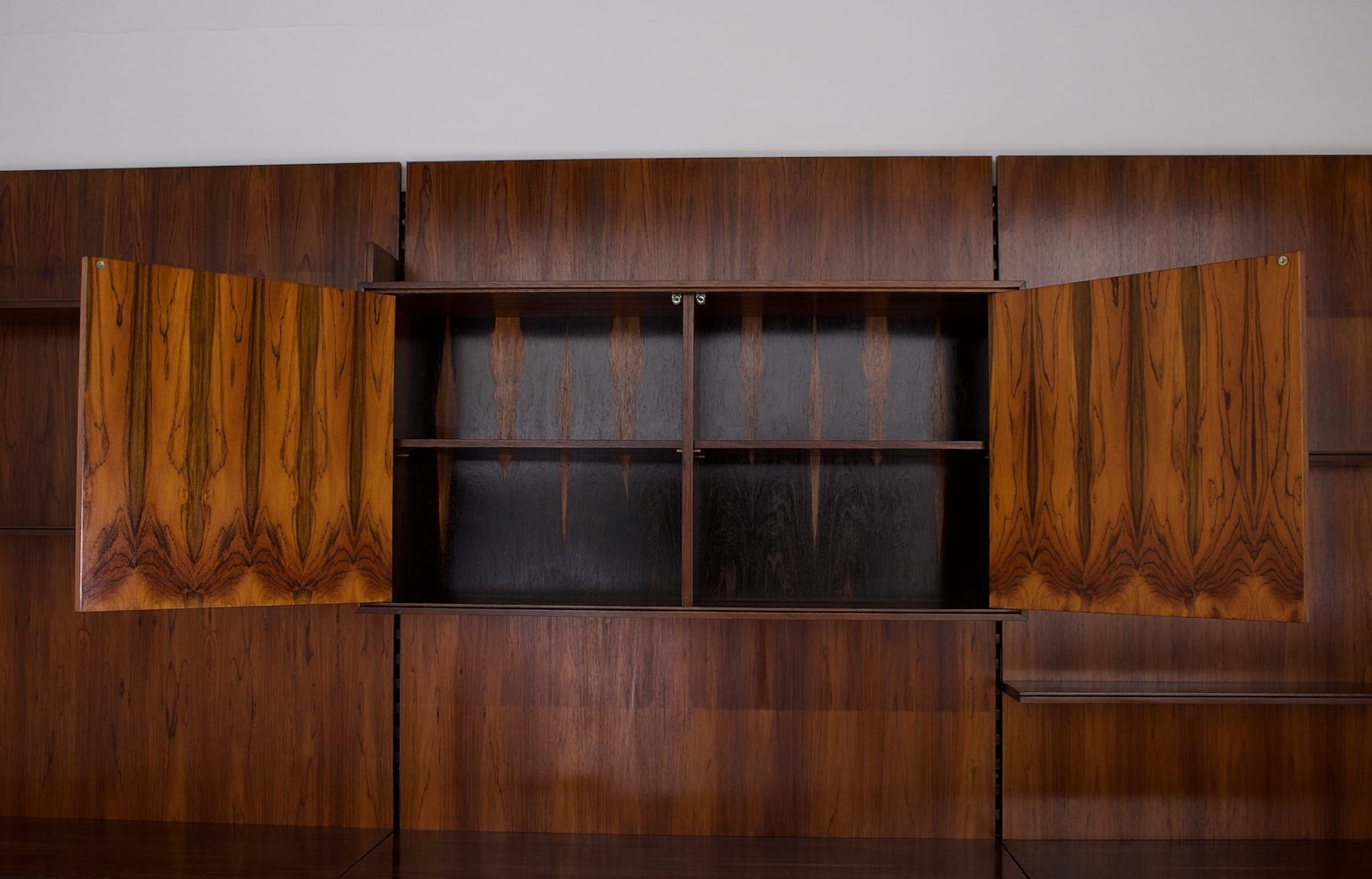 Un gros plan sur l'intérieur d'un des caissons de l'étagère murale en palissandre