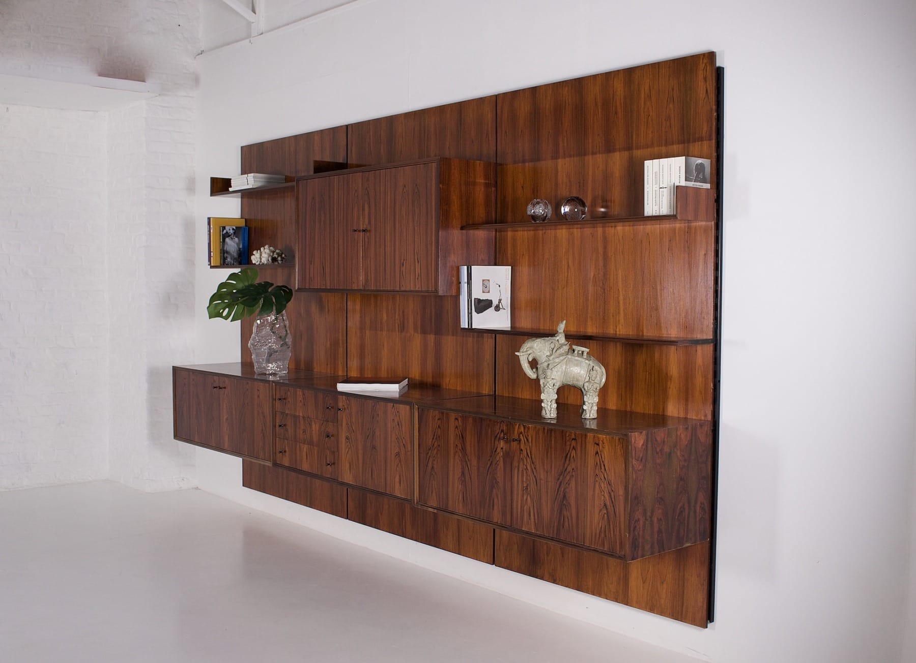 Livres, magazines et objets de décoration disposés sur l'étagère murale en palissandre