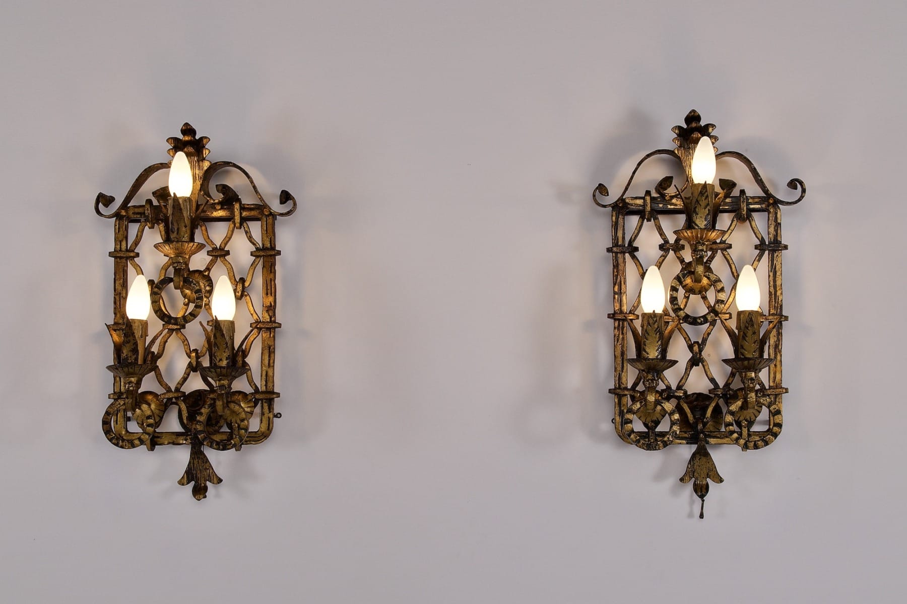Une paire d'appliques en fer forgé doré néobaroques style Gilbert Poillerat, éclairées