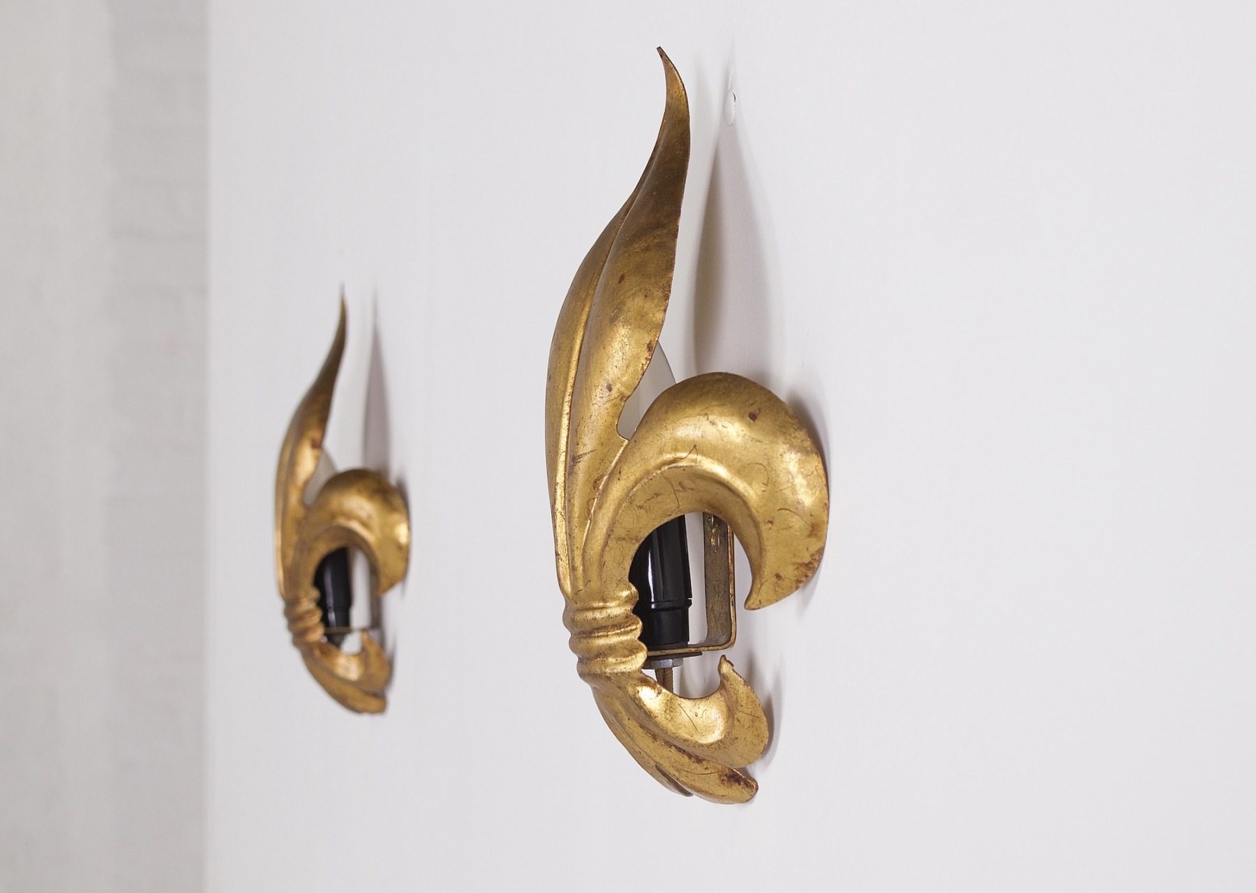 Une paire d'appliques en fer forgé doré. "Fleur de Lys" de profil et éteinte