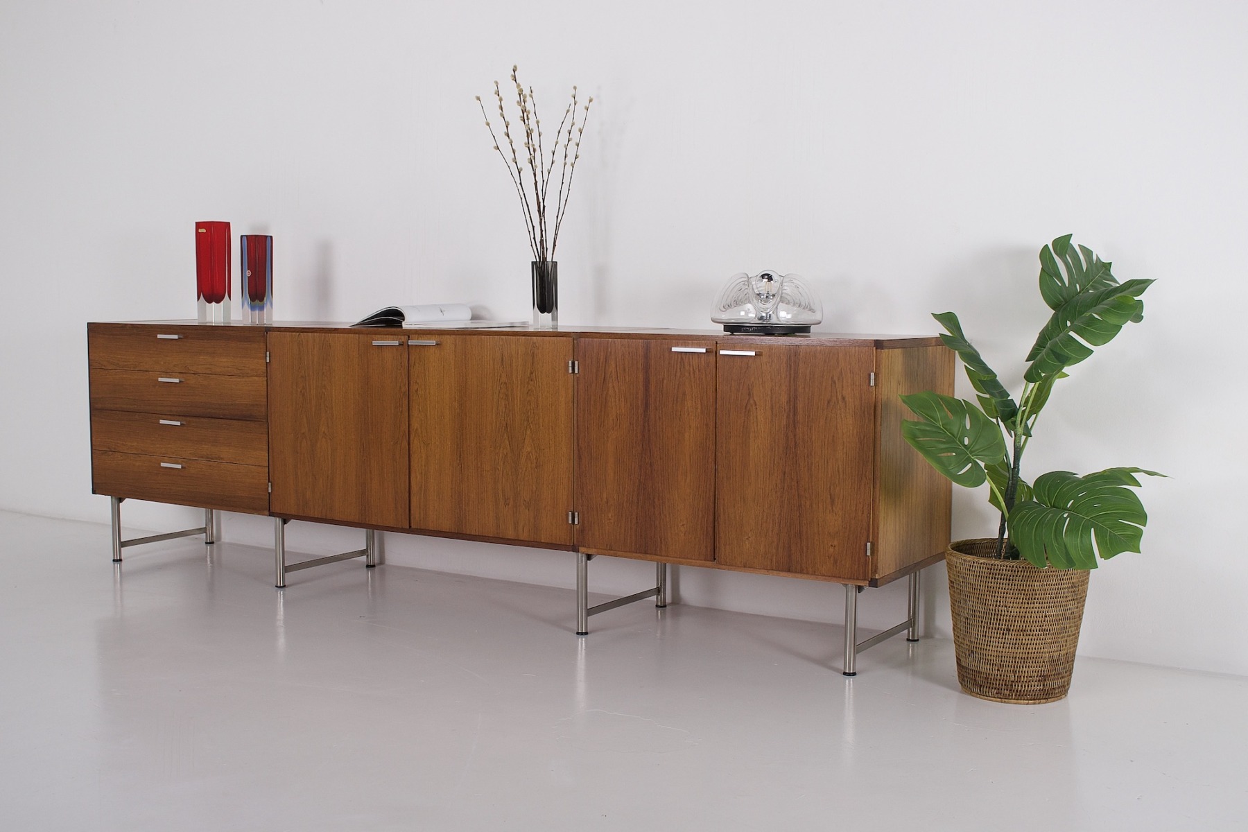 Une enfilade en palissandre de Cees Braakman pour Pastoe, une plante, 3 vases en cristal, un magazine et une lampe cinétique