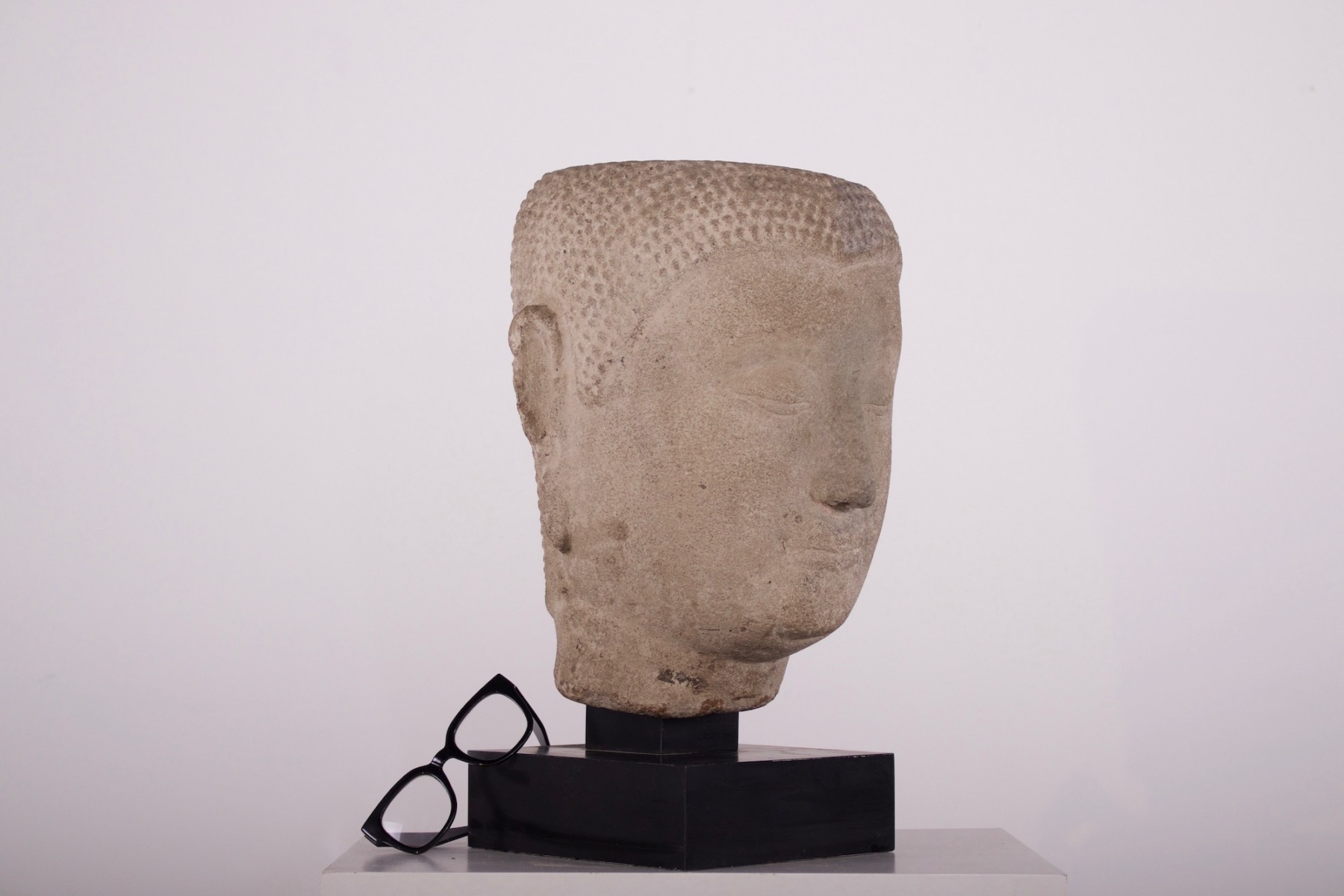 Authentique tête de Bouddha en pierre grès d'époque Ayutthaya provenance Claude de Marteau à côté de lunettes