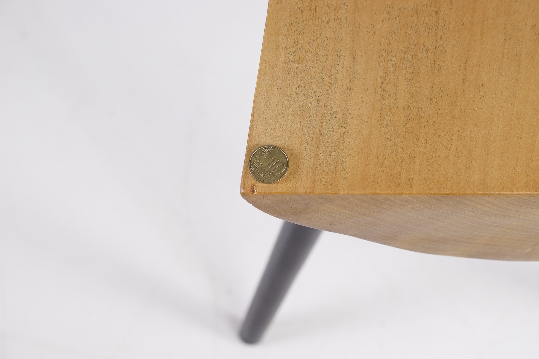 Une légère marque d'usure sur un des côtés du petit banc, table basse Wabi Sabi, une pièce de 10 cents marque l'échelle