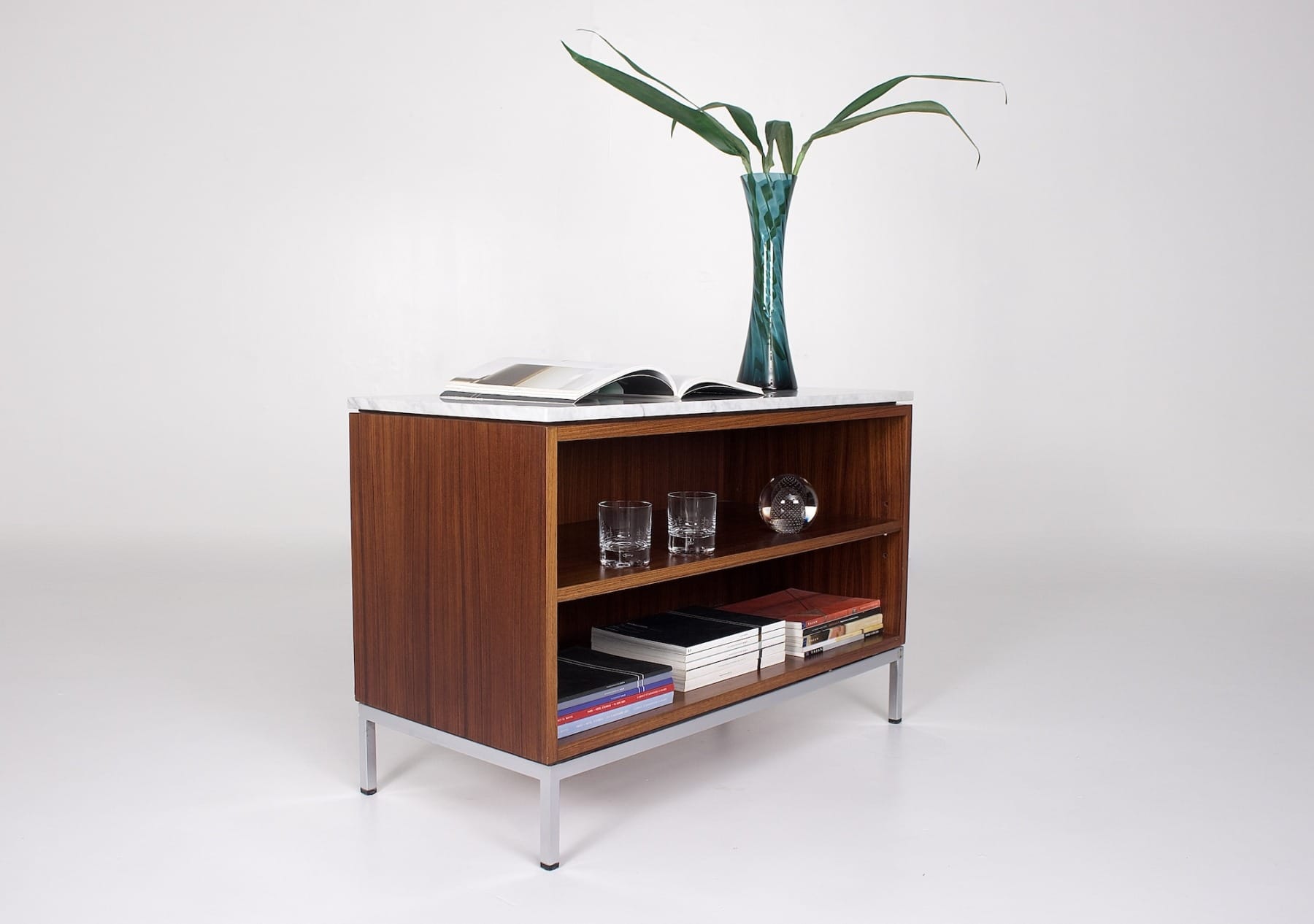 Petit buffet bas en palissandre avec tablette en marbre, décoré d'un vase bleu et de revues