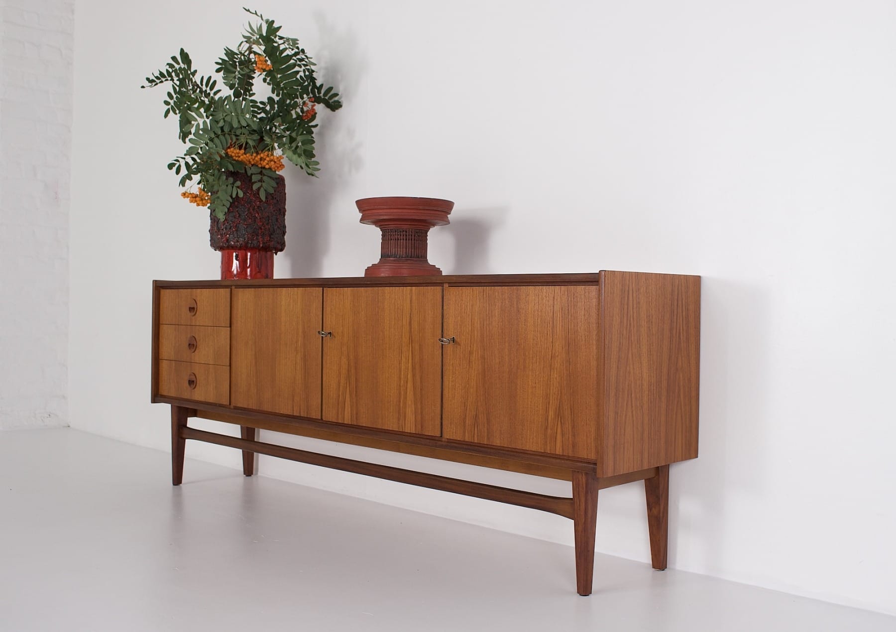 Low 1960s storage unit in Scandinavian style with red vases