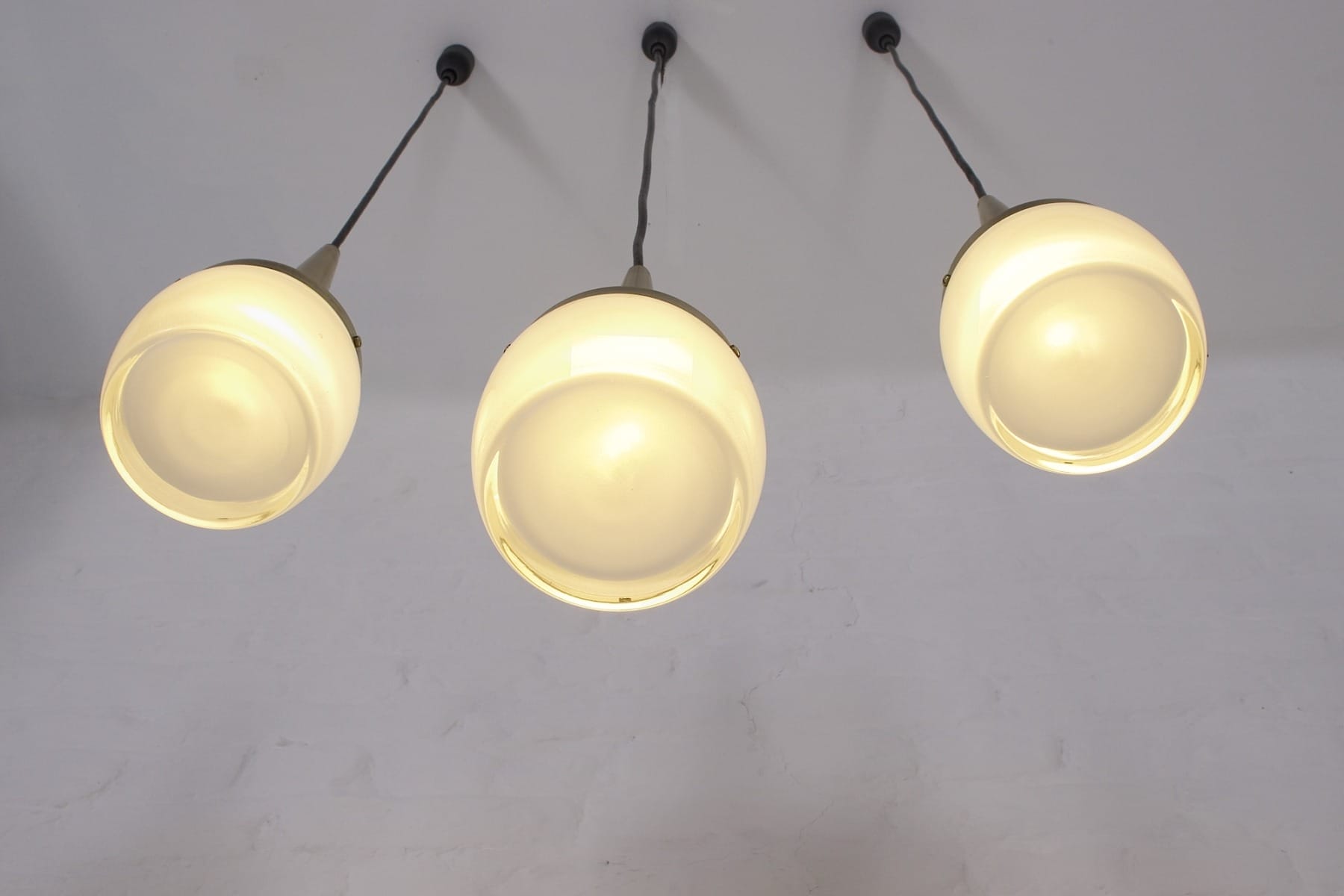 Die 3 Pendelleuchten aus Metall und Glas in Tulpenform von unten beleuchtet