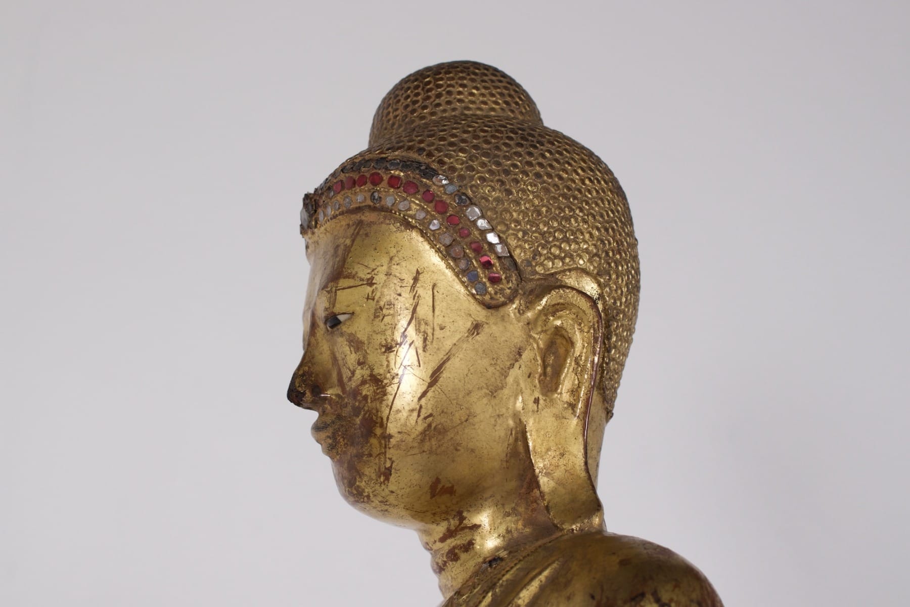face of a standing Buddha holding the myrobalan fruit, profile face