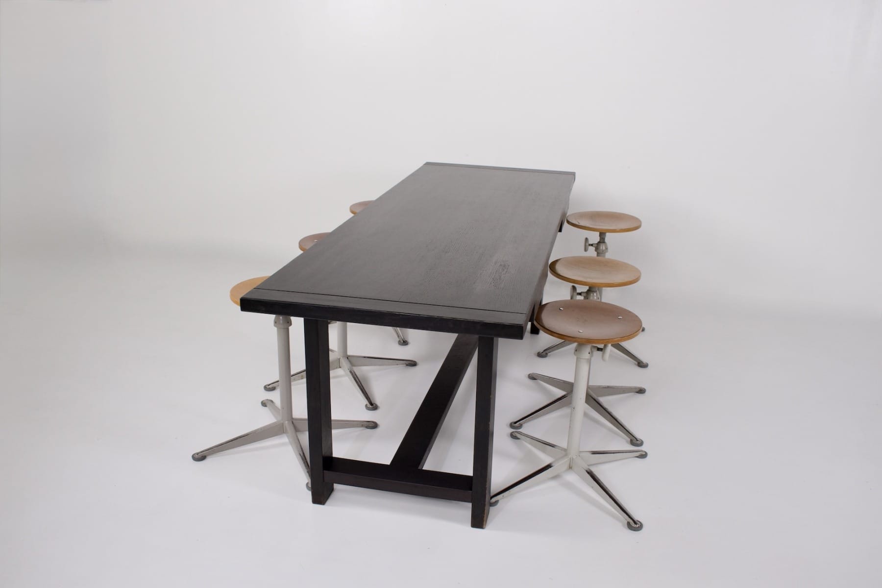 Tabourets acier et bois De Cirkel placés autour d'une table brutaliste noire